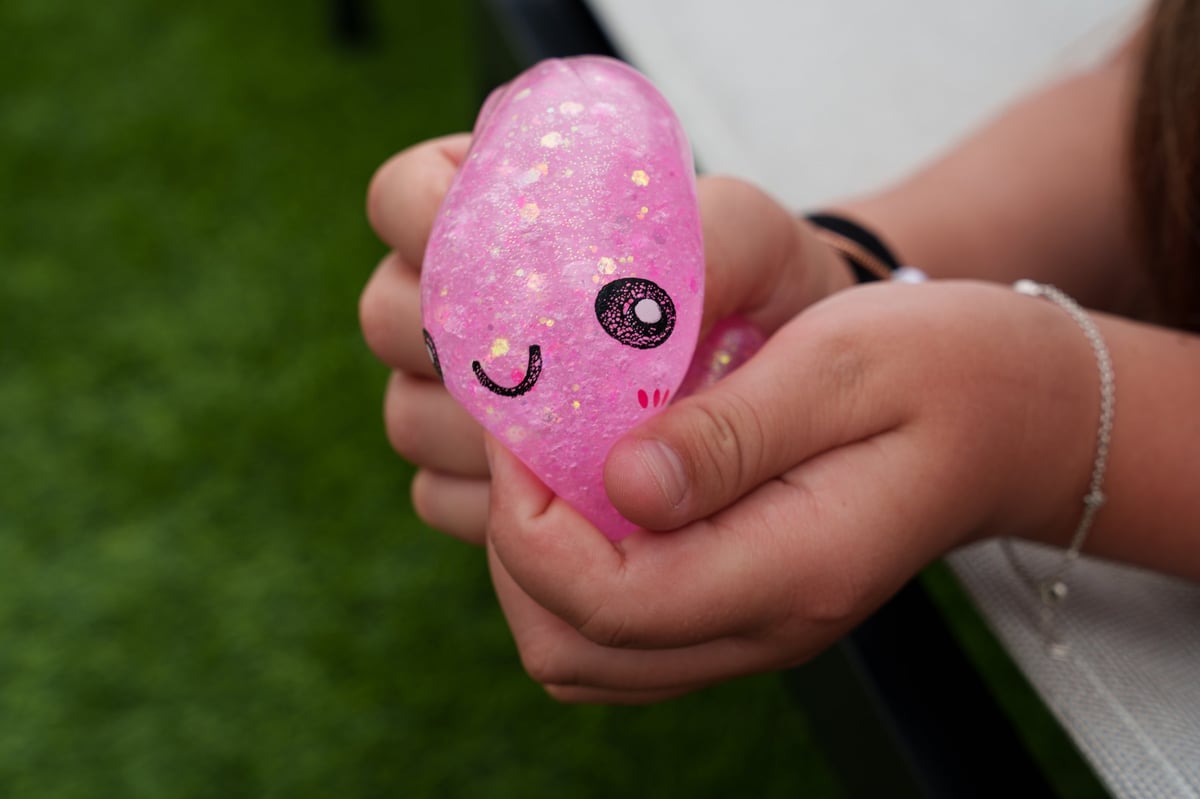 A child's hand squeezing a pink glitter squishy dumpling toy